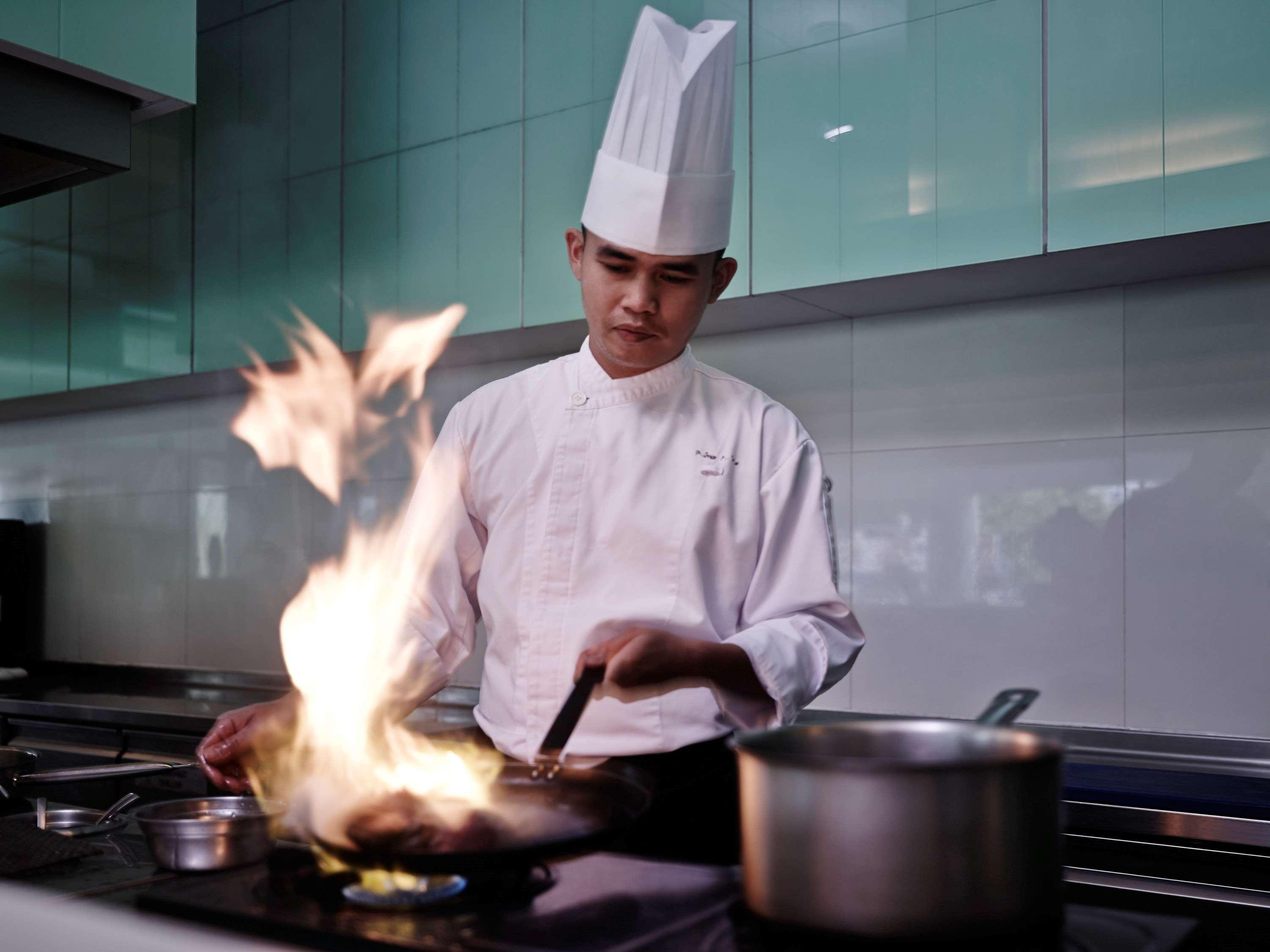 فندق بولمان كوشنغ كوشنج المظهر الخارجي الصورة A chef cooking with a flaming wok